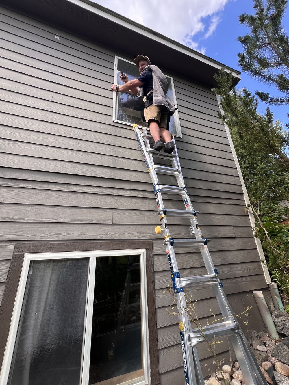 Corey cleaning an upper-story window from a ladder